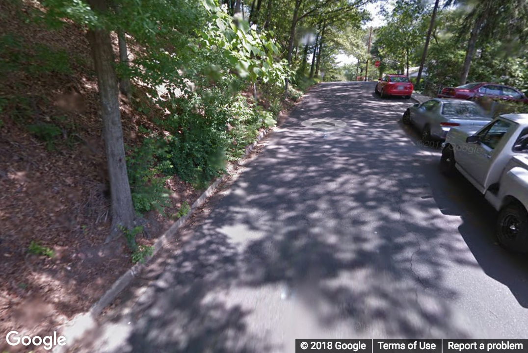 A Street View image of a road that is missing a sidewalk on the left side