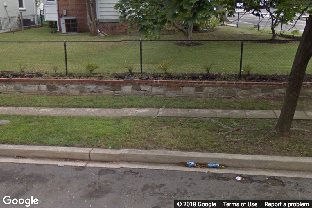 A Street View image of an extended stretch of narrow sidewalk less than 3ft wide