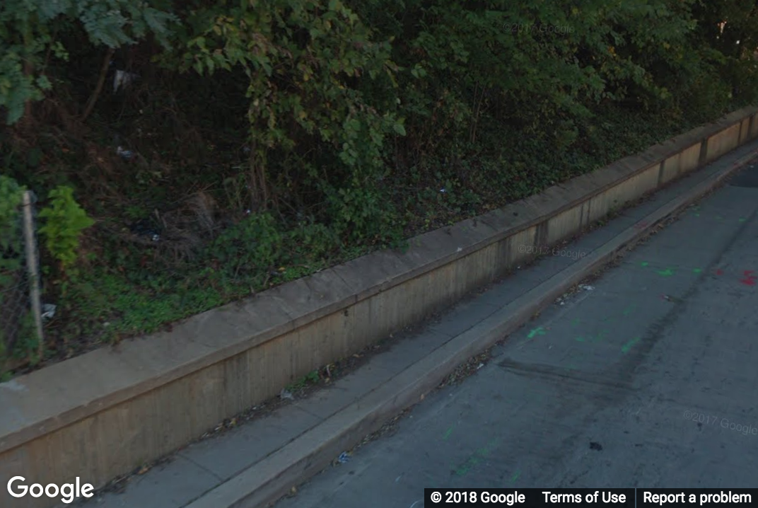 A Street View image of an extended stretch of narrow sidewalk less than 3ft wide